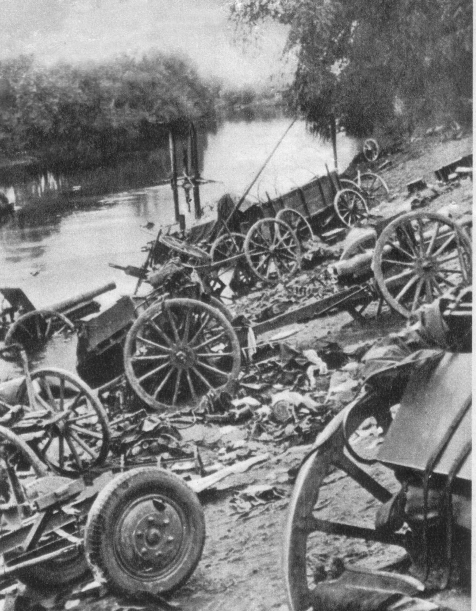 Canhões e carroças de rodas de madeira abandonados e destroçados na margem de um rio