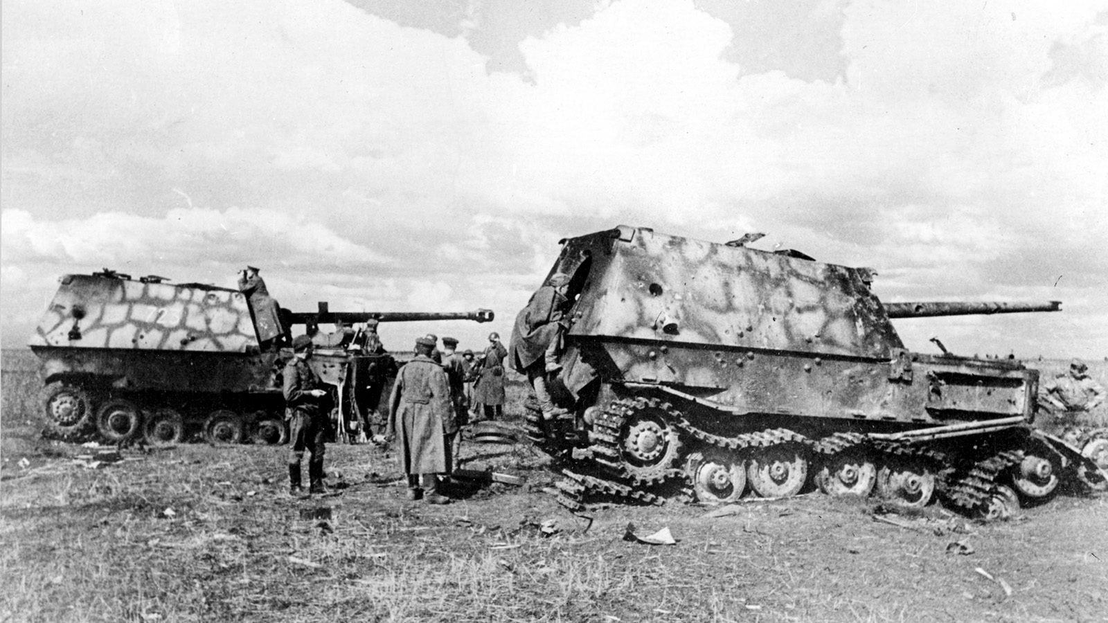Dois caça-tanques alemães Ferdinand destruídos num campo aberto, com o casco crivado e as lagartas soltas, enquanto soldados soviéticos de capote os examinam